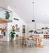 Dining table in open plan living room with concrete floor and gallery
