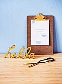 Golden decorative writing and clipboard with a saying on a light blue wall