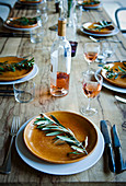 Mediterran gedeckter Tisch mit Rosewein und Olivenzweigen als Tellerdeko