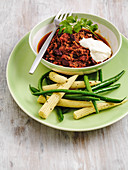 Chilli con carne with sour cream and coriander served with baby corn and beans