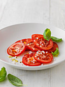 Tomato salad with chopped shallots served with basil leaves