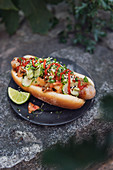 A hot dog made with a German sausage, kimchi and sesame seeds