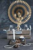 Candles on chopping board in front of bottles in wooden crate