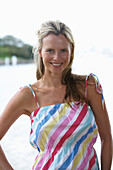 A young blonde woman on a beach wearing a light-blue top