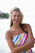 A young blonde woman on a beach wearing a light-blue top