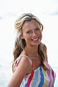 A young blonde woman on a beach wearing a light-blue top