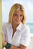 Junge blonde Frau in weißer Bluse am Strand