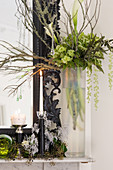 Vase of green flowers and branches on mantelpiece