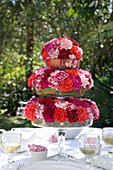 Carnations in shades of red arranged on cake stand on set table in garden
