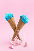 Blue colored bright ice cream served in waffle cone with marshmallow