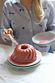 A woman glazing a Bundt cake