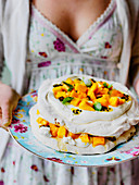 Easter mango and passion fruit pavlova being held by girl in floral dress