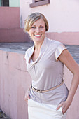 A blonde woman wearing a light blouse and a white skirt