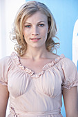A blonde woman wearing a pink short-sleeved blouse