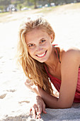 A young blonde woman on a beach wearing a pink top