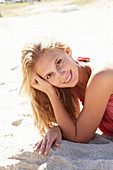 A young blonde woman on a beach wearing a pink top