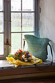 Crocheted bag and bouquet of flowers on sill of rustic window