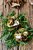 Bruschette with ruccola olive oil and grillled mushrooms on wooden background