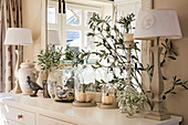 Table lamps, olive branches and glass vessels on sideboard
