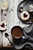 Eine Tasse heiße Schokolade serviert mit Marmeladeplätzchen auf Holztisch