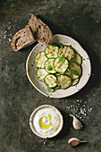 Grilled zucchini salad with yogurt dip, garlic and rye sliced bread in spotted ceramic plates