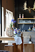 Vase of delphiniums and DIY flower arrangement with driftwood on kitchen table