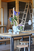 Driftwood arranged in zinc bucket and decorated with summer flowers in glass vases