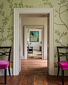 Wall paper around doorway flanked by pair of dining chairs upholstered in velvet