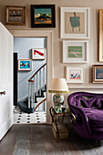 A purple sofa upholstered in velvet in living room with assorted artworks