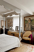 Frisierkommode, Sessel, darüber Gemälde im Schlafzimmer mit verspiegeltem Himmelbett
