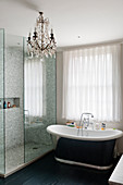 Frei stehende Badewanne im Badezimmer mit Mosaikfliesen und Kronleuchter