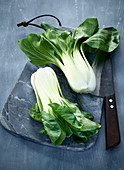 Bok choy on a grey marble board with a knife