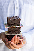 Mädchenhände halten einen Stapel Schokoladenkuchenstücke