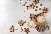Eggnog Christmas milk cocktail, served in two vintage crystal glasses on wooden tray with shortbread star shape sugar cookies, cinnamon sticks