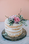 A small sponge wedding cake (naked cake) with vanilla buttercream and lemon curd on a wooden slab
