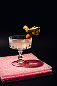 A White Lady Cocktail, garnished with physalis on a pink background