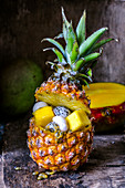 Fruit salad in pineapple on a wooden background