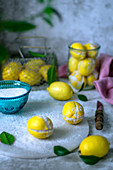 Salted preserved lemons on a gray surface and fresh lemons
