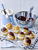 Profiteroles a la creme on rack with melted chocolate and cream