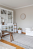 White glass-fronted cabinet and white bamboo baskets in corner
