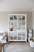 White glass-fronted cabinet and white bamboo baskets in corner