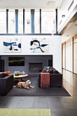 Lounge area with black upholstered furniture, fireplace and television in high room