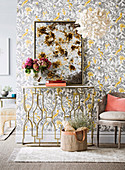 Delicate console table in front of a wallpaper with leaf motif in gray