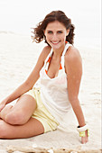 Brünette Frau in weißem Top und Shorts am Strand
