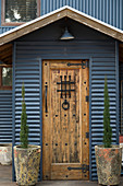 Rustikale Holztür mit Metallbeschlägen am Wellblechhaus