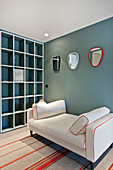 Pale couch and floor-to-ceiling shelving in room with petrol-blue wall