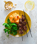 Beef skewers with mashed sweet potatoes and cashew nuts