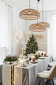 Cane lampshades above festively set dining table in natural shades