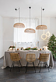 Korb-Leuchten überm weihnachtlich gedeckten Tisch in Naturtönen