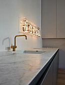 Leuchtschrift über der Spüle in minimalistischer Küche